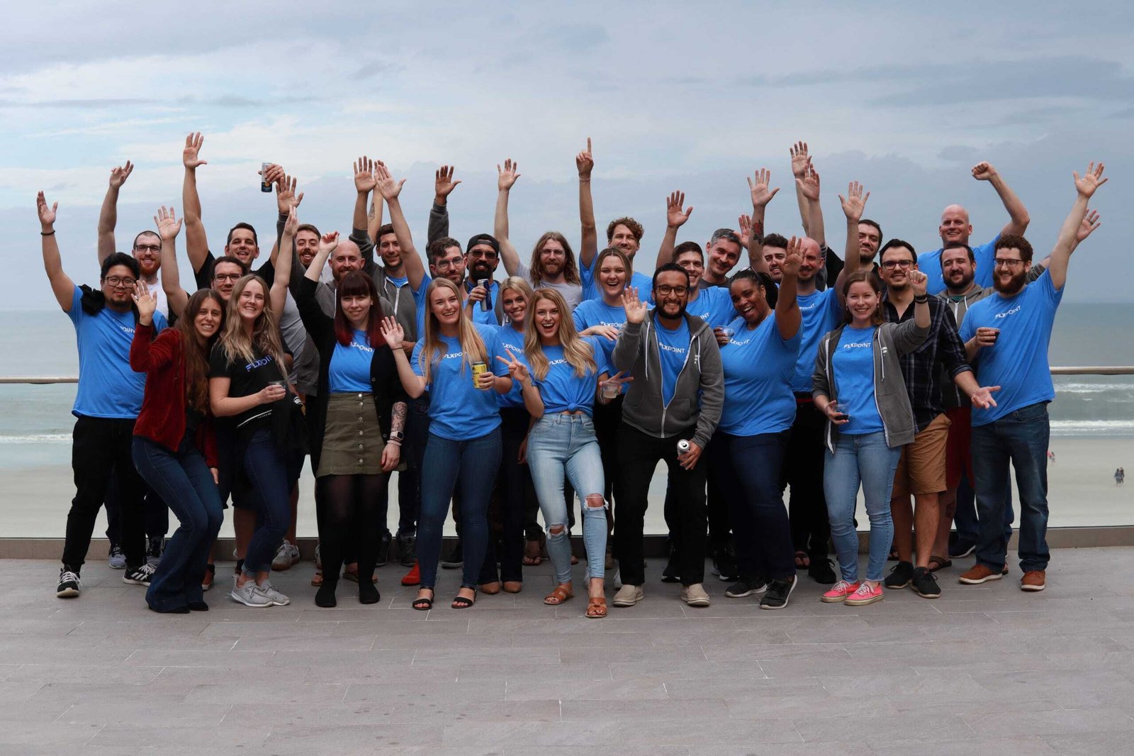 The Flxpoint team together outdoors, waving at the camera